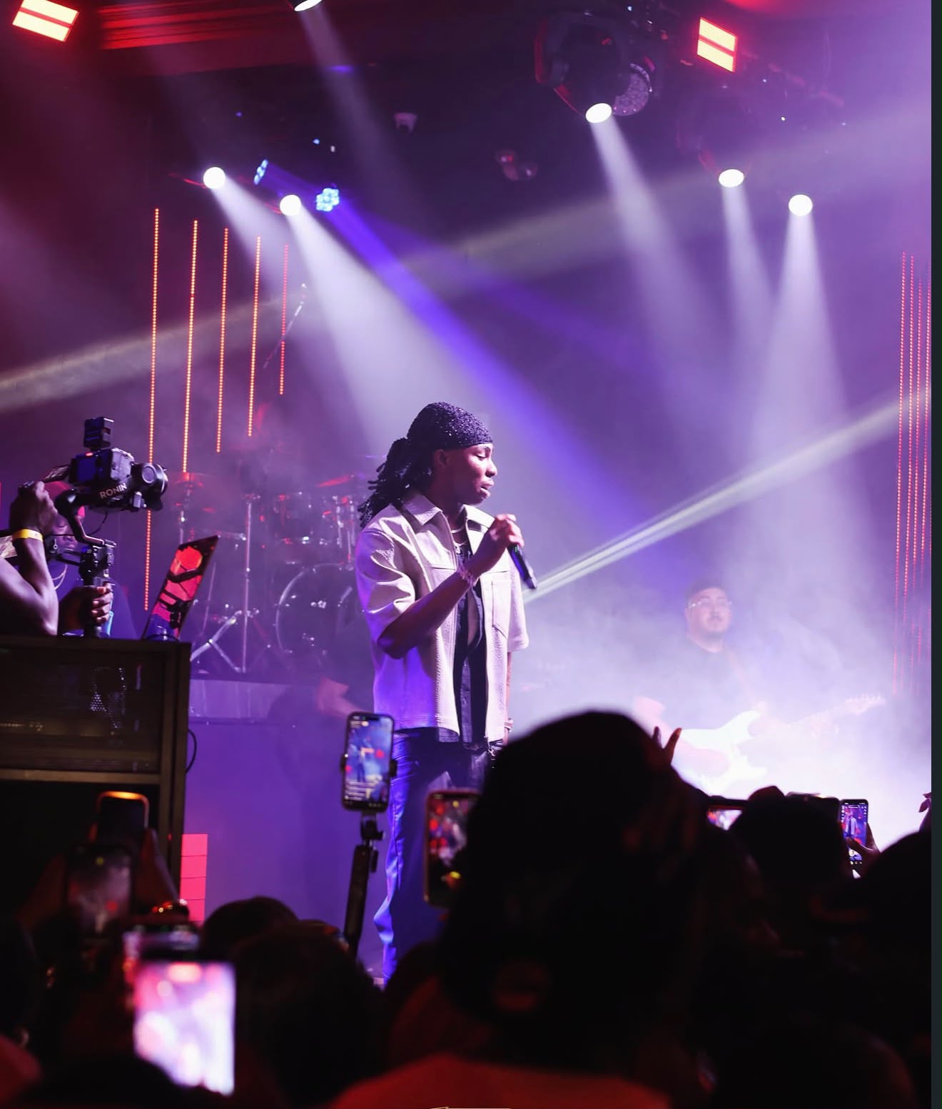 Singer performing with a live band under spotlights