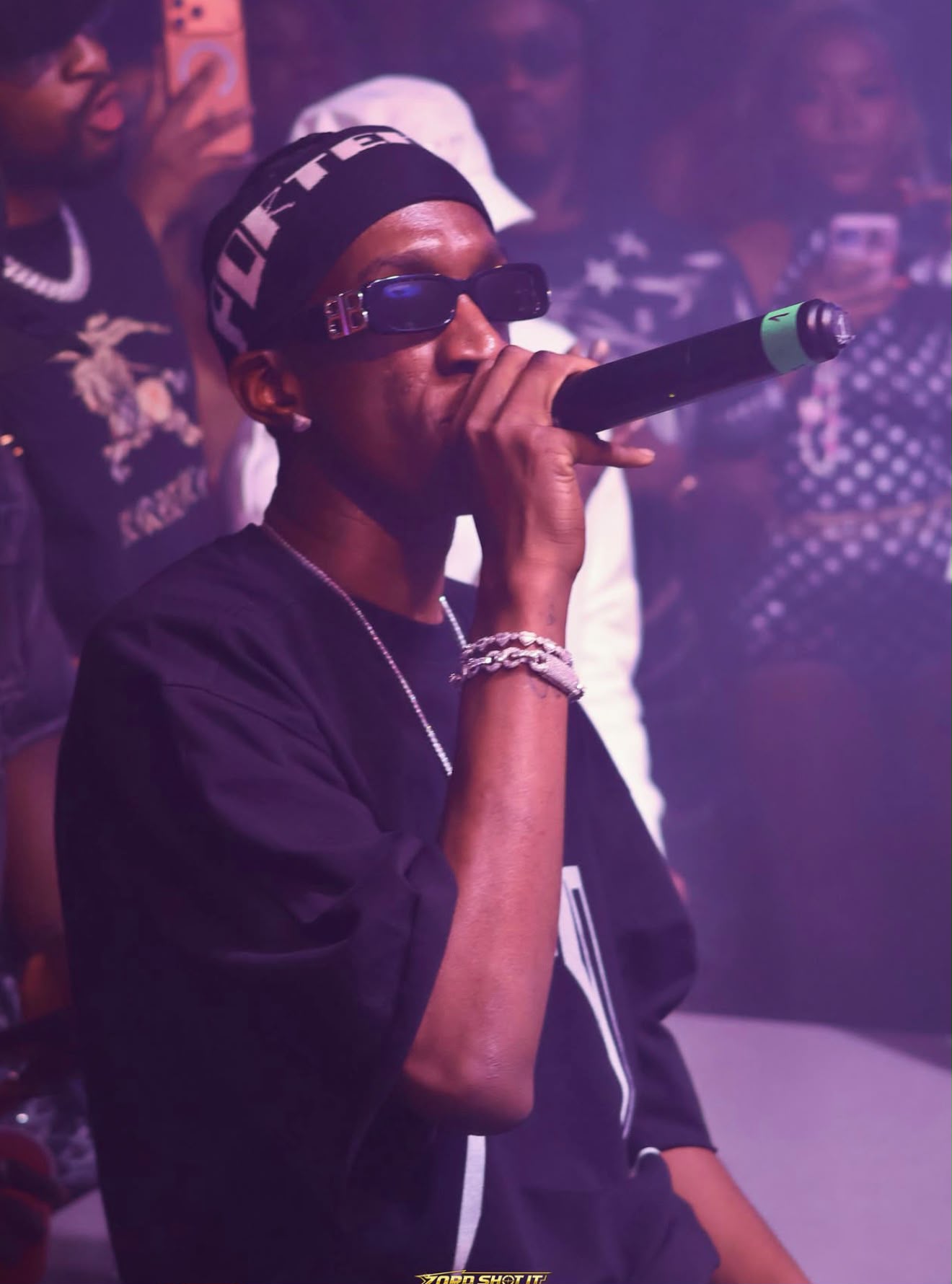 Artist performing live under purple stage lights