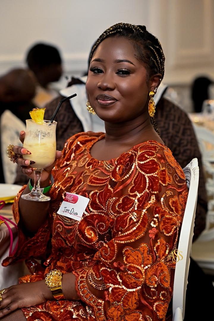 Guest in orange sequinned attire holding a cocktail at a dinner event